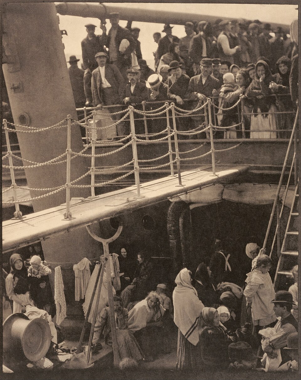 Passengers crowded on two decks of a ship, divided by a bright diagonal gangway